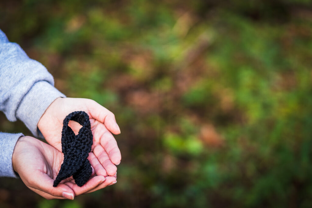 A person holding a black ribbon in support of cancer